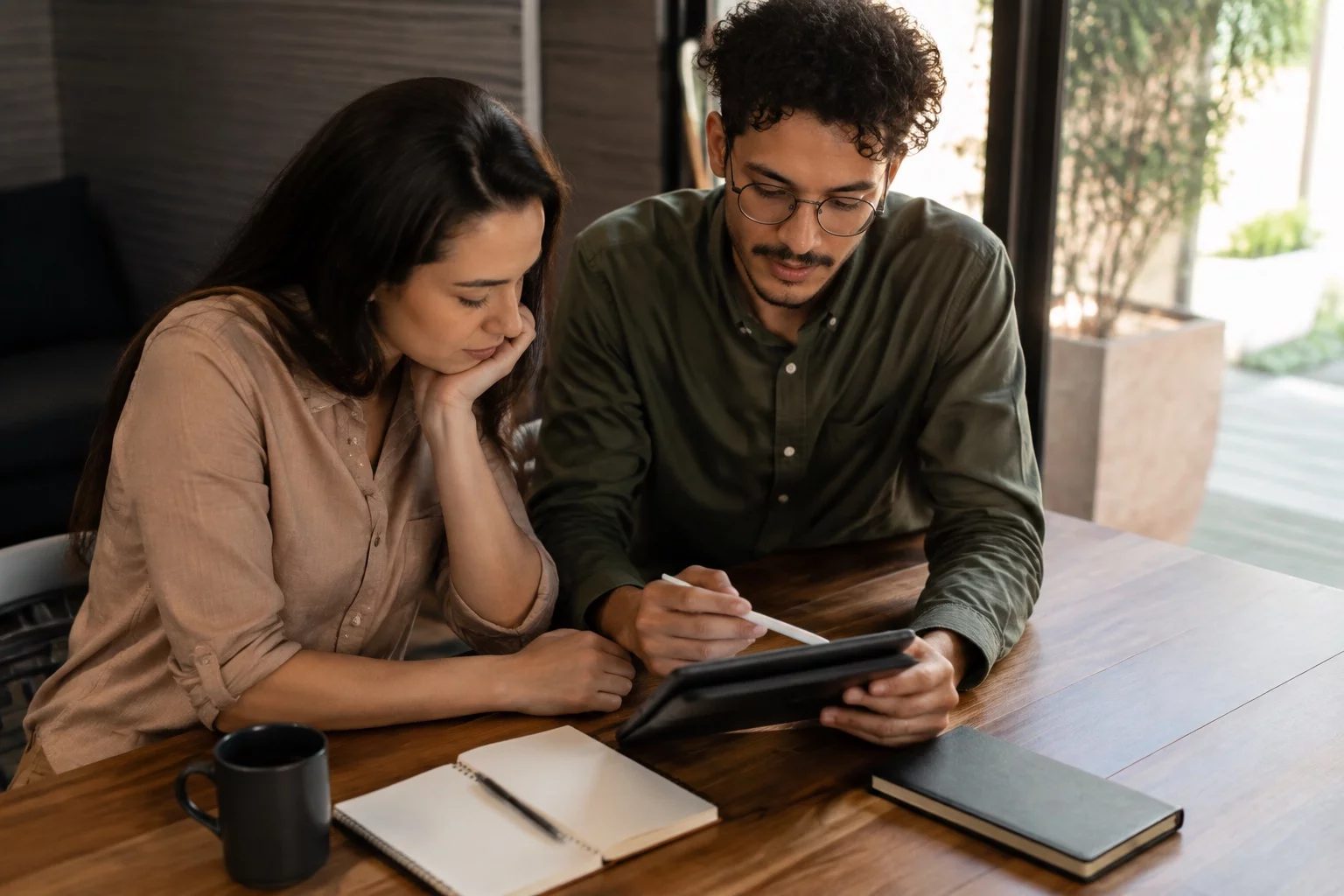Duas pessoas revisando anotações em um tablet sobre uma mesa de madeira